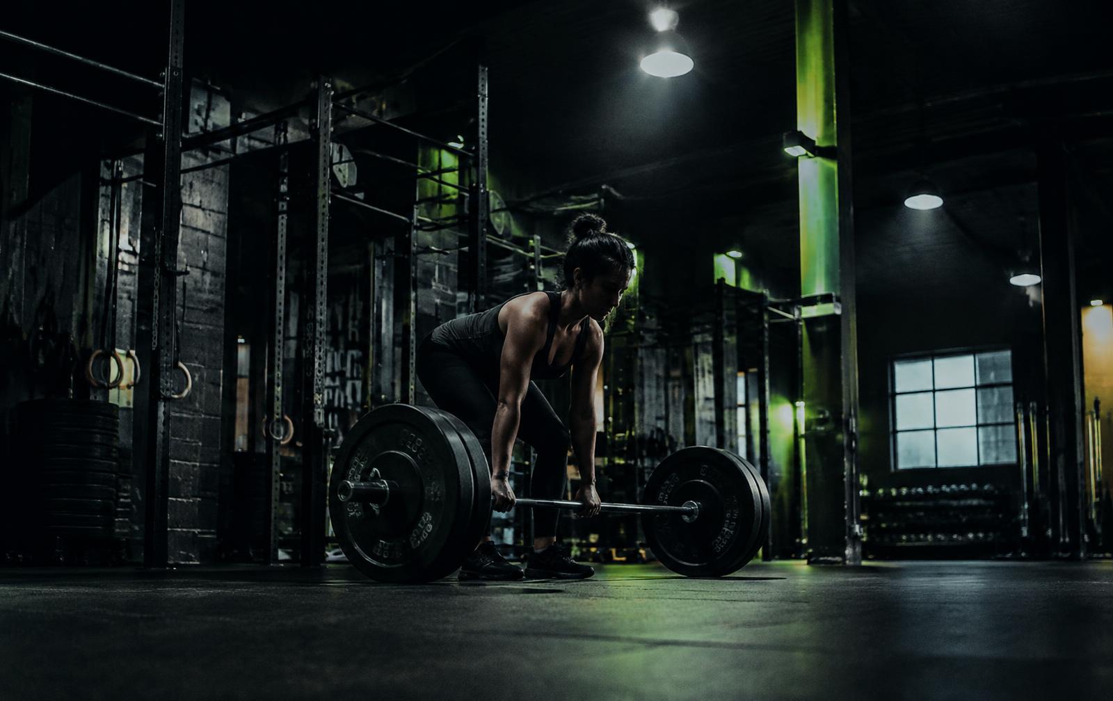 Athlete deadlifting in a dark industrial gym